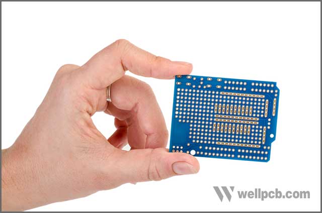 Blue prototyping PCB in a hand isolated on the white background.jpg