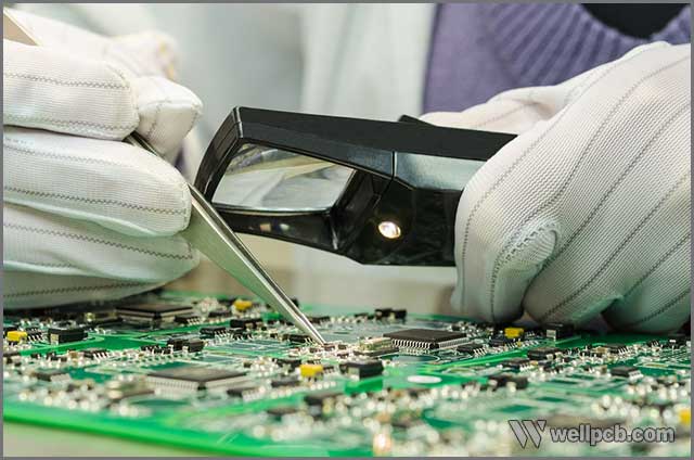 a PCB technician inspecting the solder joints on a board.jpg