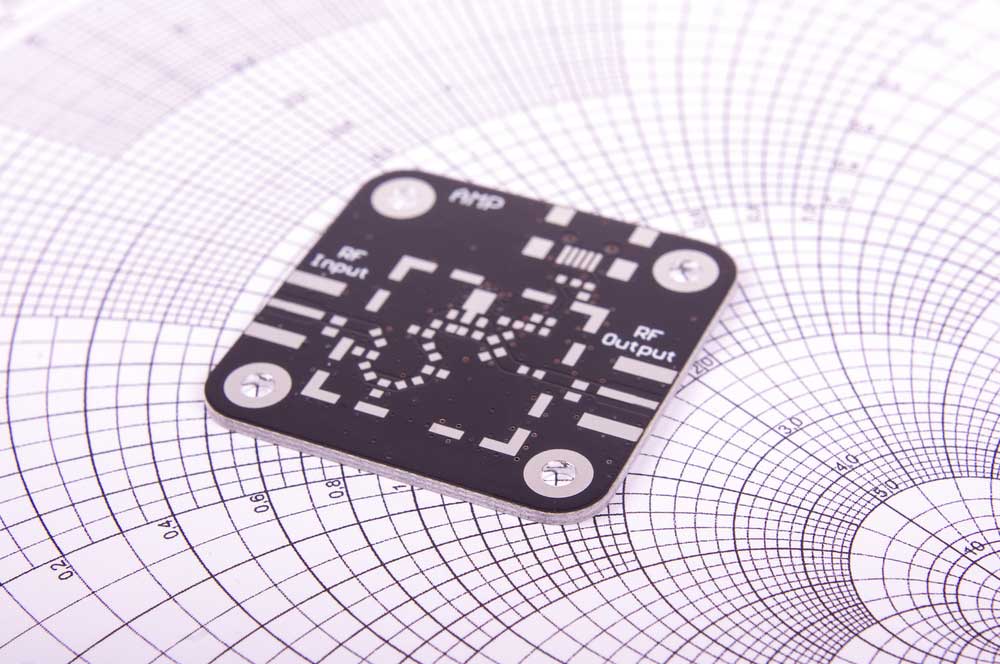 A hand holding tweezers on an electric circuit