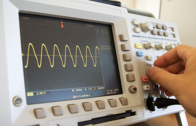 A hand adjusting an oscilloscope