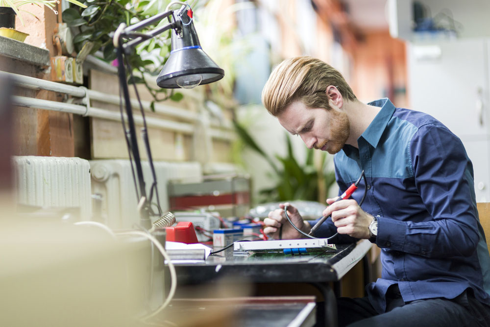 A Young Man Soldering a Circuit Board