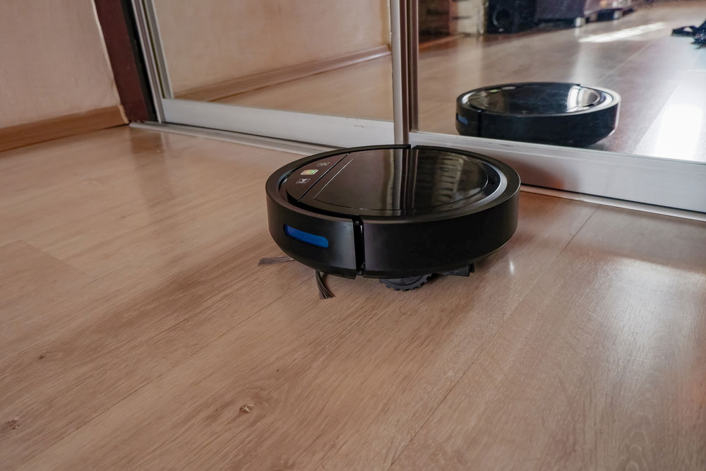 The Robot Vacuum Cleaner Vacuums the Floor in the Apartment