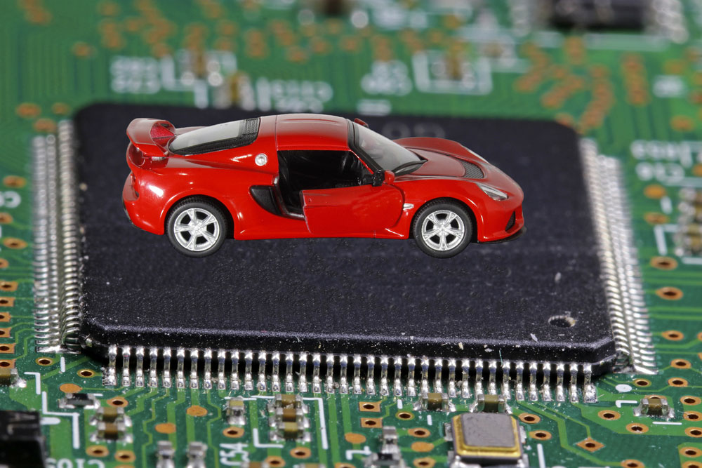 The red car stands on the microprocessor. The concept of a shortage of chips in the automotive industry